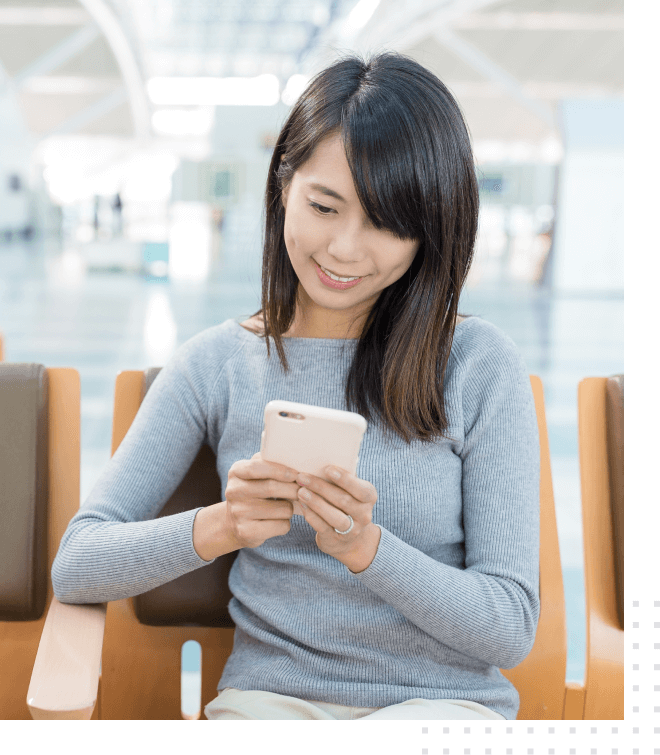 A woman sits with a smartphone and uses a mobile hotel application, big image